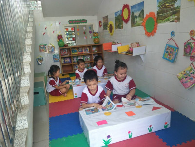 Bé tham gia đọc sách tại góc thư viện trường MN Hoa Mai.